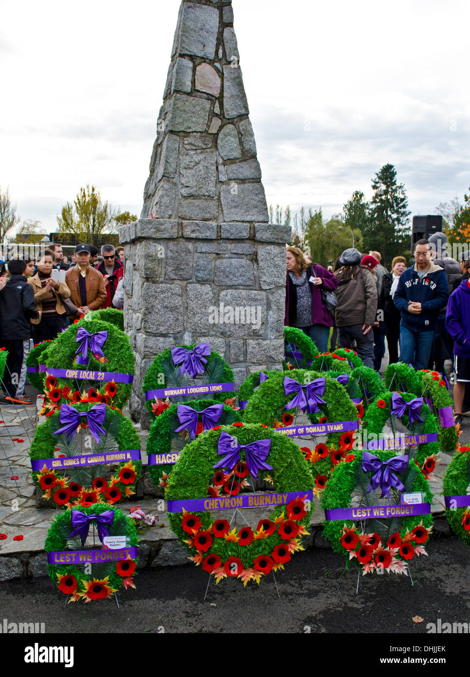 BURNABY, BRITISH COLUMBIA, CANADA – Monday November 11, 2013:  People observing the cenotaph decorated with wreaths and poppies following the Remembrance Day service in Confederation Park, Burnaby, BC. Canada.  Hundreds of people from the community gathered for the annual ceremony, to show respect and thanks to war veterans past and present. Stock Photo