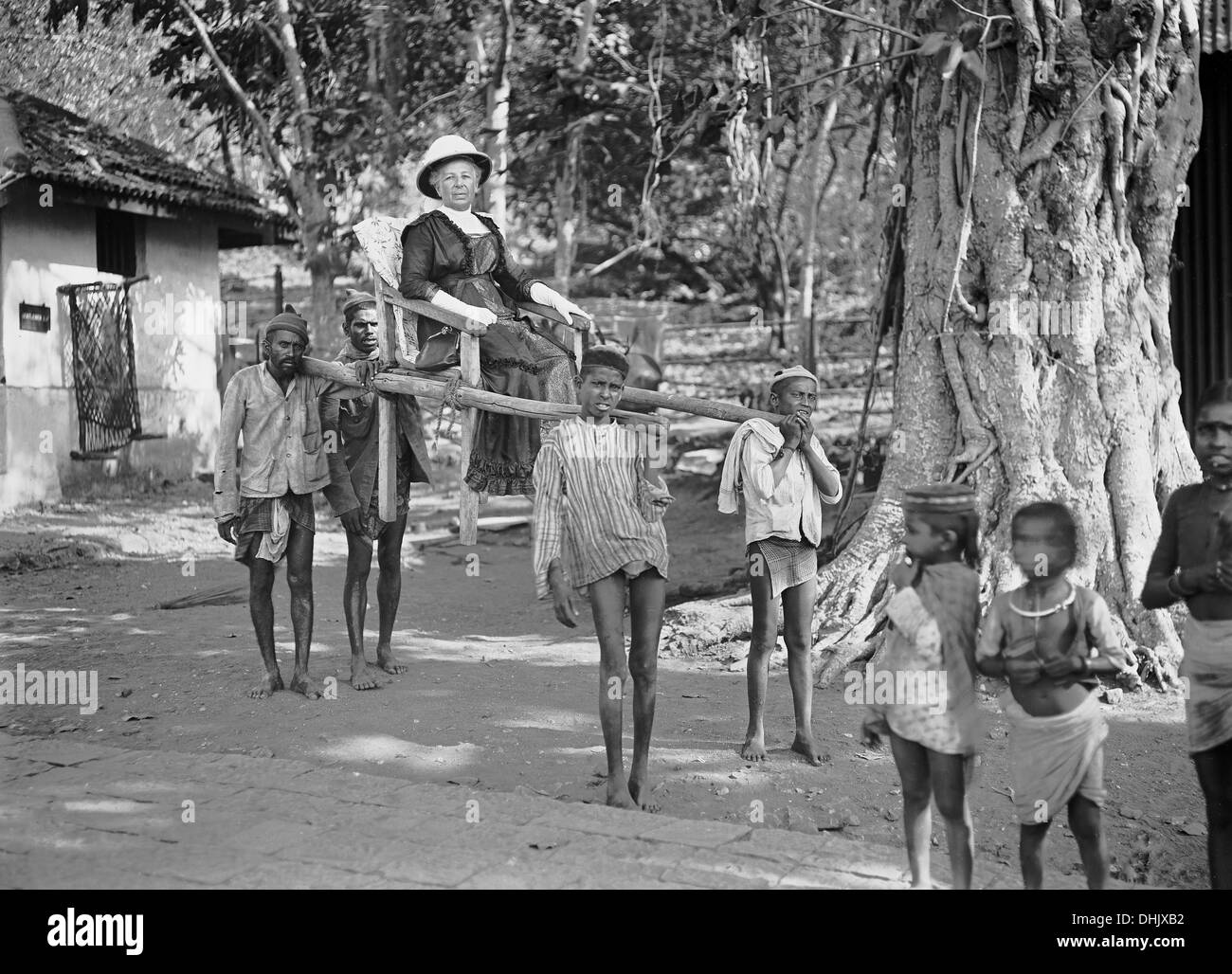 A tourist is pictured in a carrier chair with local carriers, undated