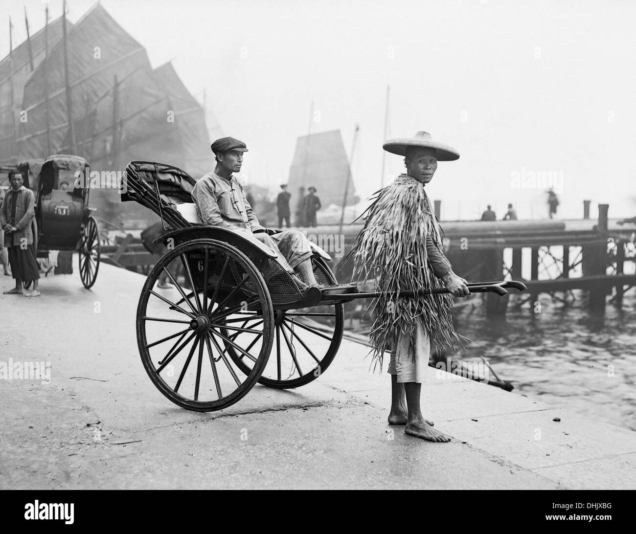 View of a rickshaw driver with passenger in the port of Hong Kong in 1912. The image was taken by the German photographer Oswald Lübeck, one of the earliest representatives of travel photography and ship photography aboard passenger ships. Photo: Deutsche Fotothek/Oswald Lübeck Stock Photo