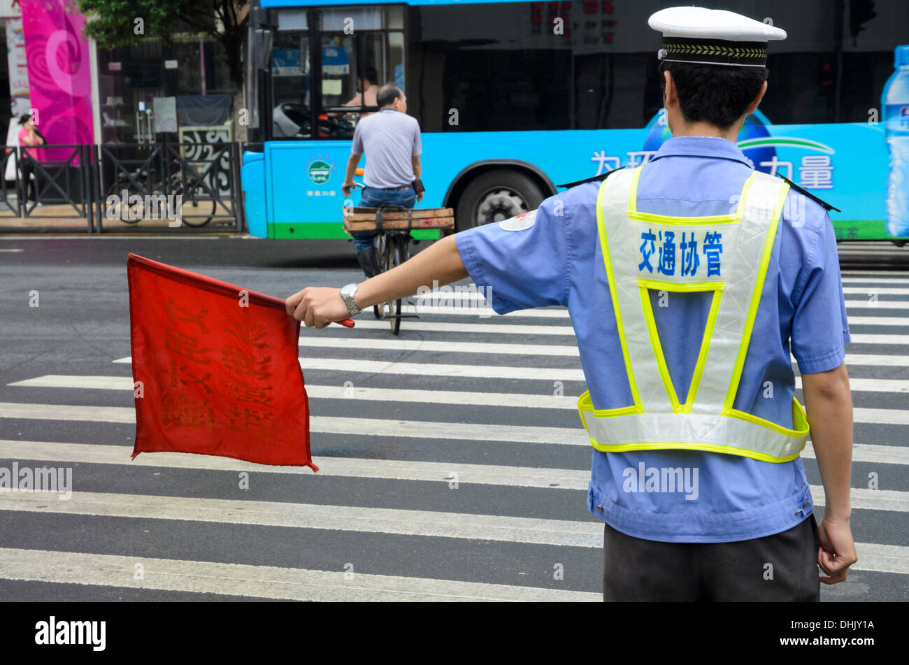 Road safety in China: Policeman directing traffic and pedestrians at a large intersection. Stock Photo
