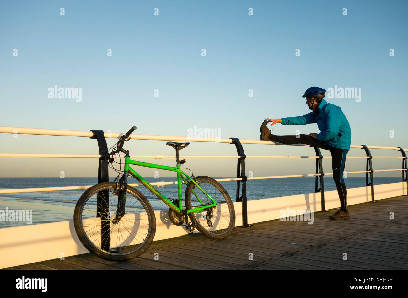 Mountain Biker stretching on Saltburn pier. Saltburn by the sea, North Yorkshire, UK. Stock Photo