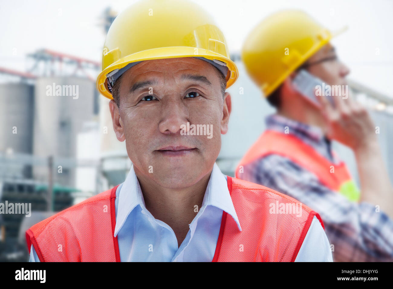 Two engineers in protective workwear working, looking at camera, outside of a factory Stock Photo
