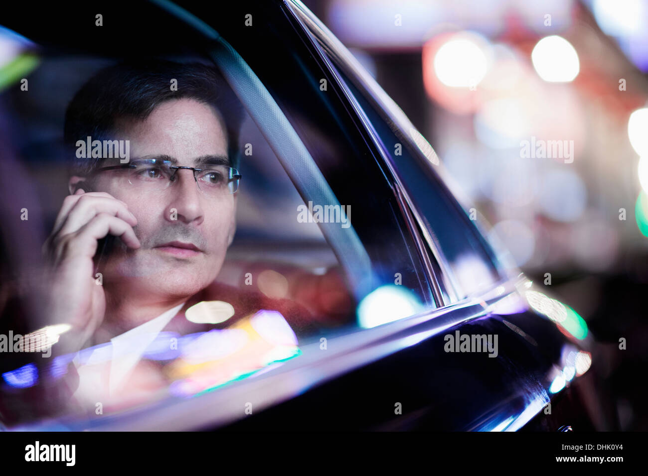Businessman on the phone and looking out the car window at night