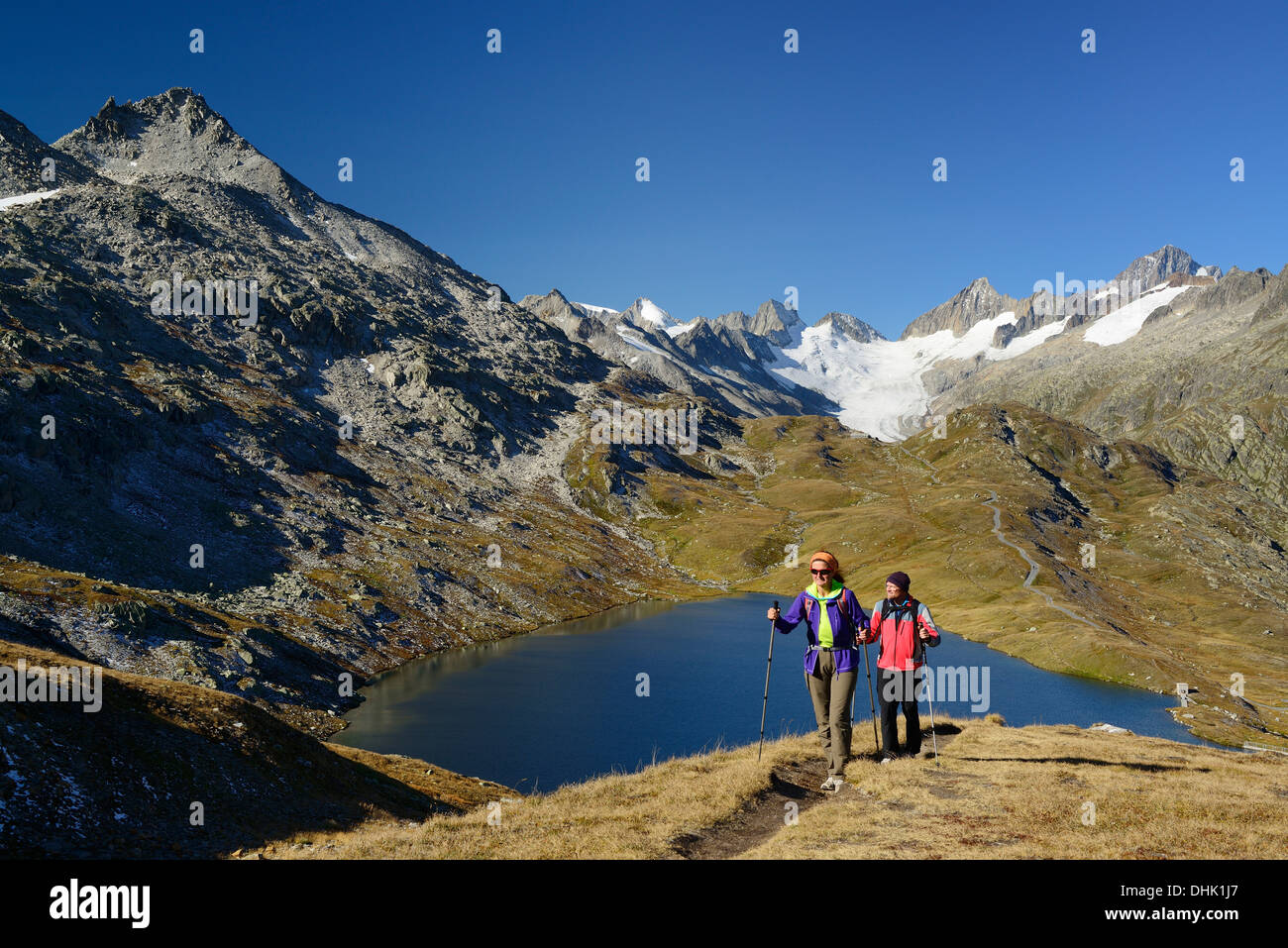 Woman and man hiking near a mountain lake with view to Oberaarhorn and Finsteraarhorn, Bernese Alps, Bernese Oberland, UNESCO Wo Stock Photo