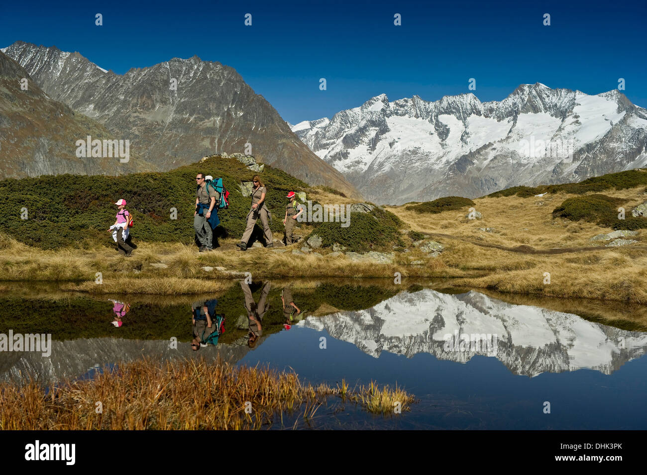 Hiking family at lake Bettmersee, Bettmeralp, in the background Bernese Oberland, Canton of Valais, Switzerland, Europe Stock Photo