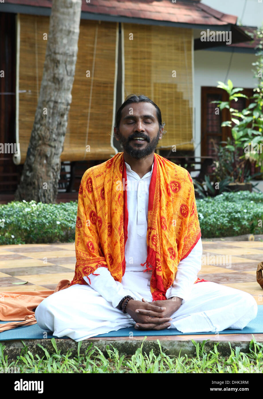 Yoga teacher sitting and chanting mantras in a resort garden in Varkala,India. Stock Photo