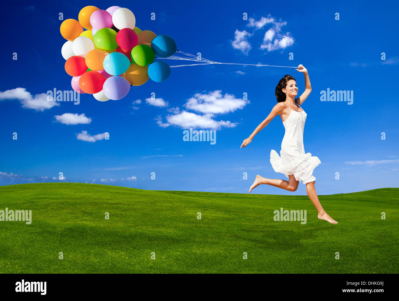 Beautiful woman running and jumping on a green meadow with a colored