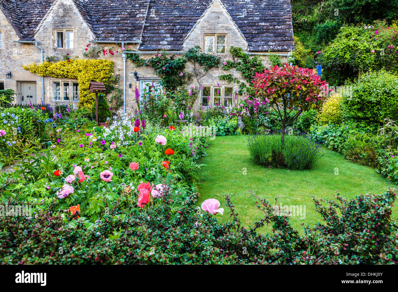 A pretty English cottage garden in the Cotswold village of Bibury in summer. Stock Photo