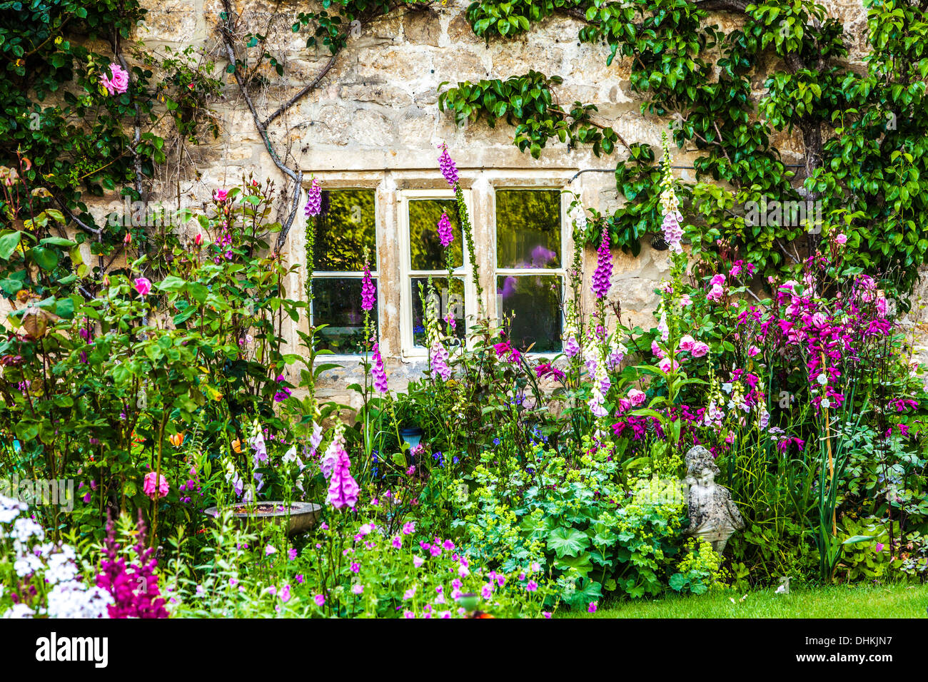 A pretty English cottage garden in the Cotswold village of Bibury in summer. Stock Photo