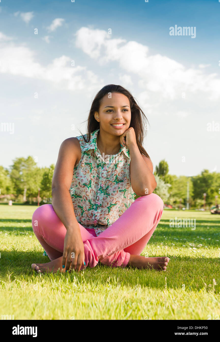 Outdoor portrait of a beautiful African American woman sitting on the ...