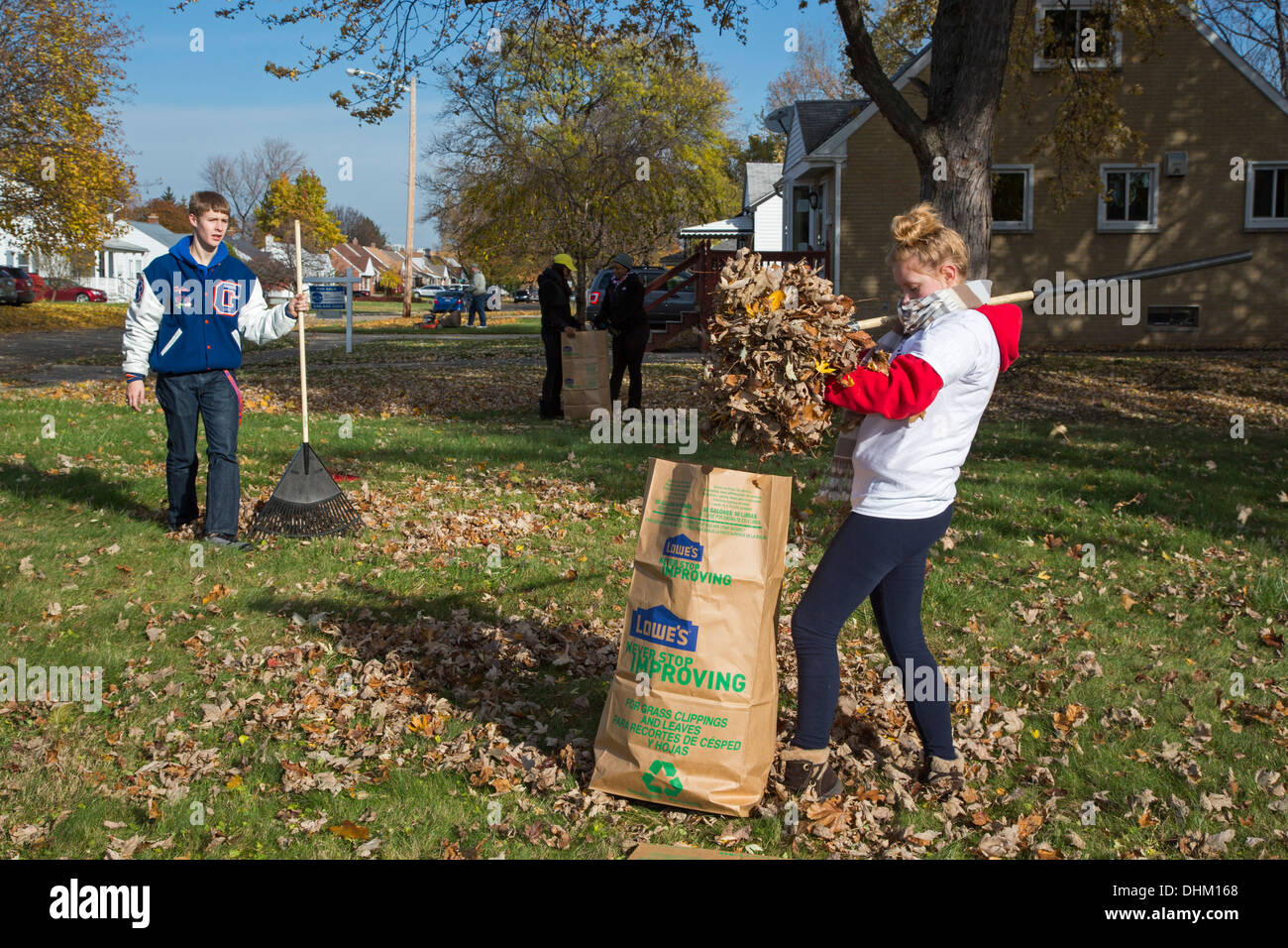 High school student volunteers rake leaves for senior citizens Stock