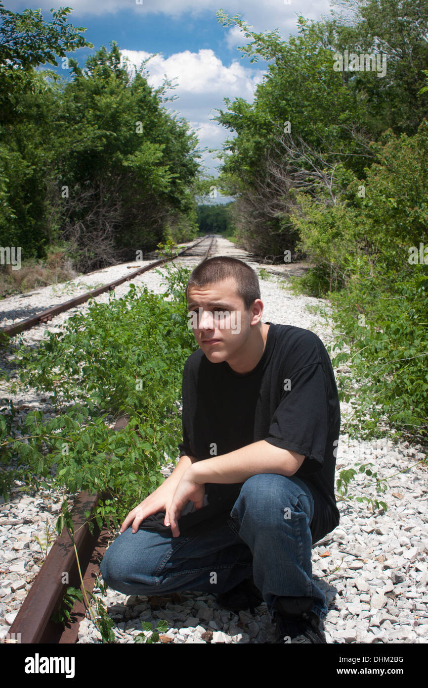 Young Man thinking along side the rail road tracks Stock Photo