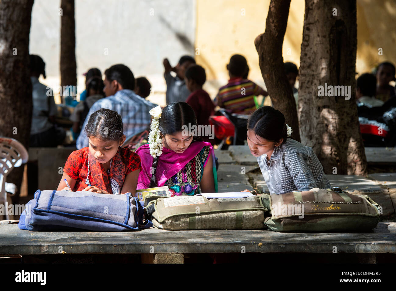 Rural Indian village school girls writing in books in an outside class. Andhra Pradesh, India. Selective focus. Stock Photo