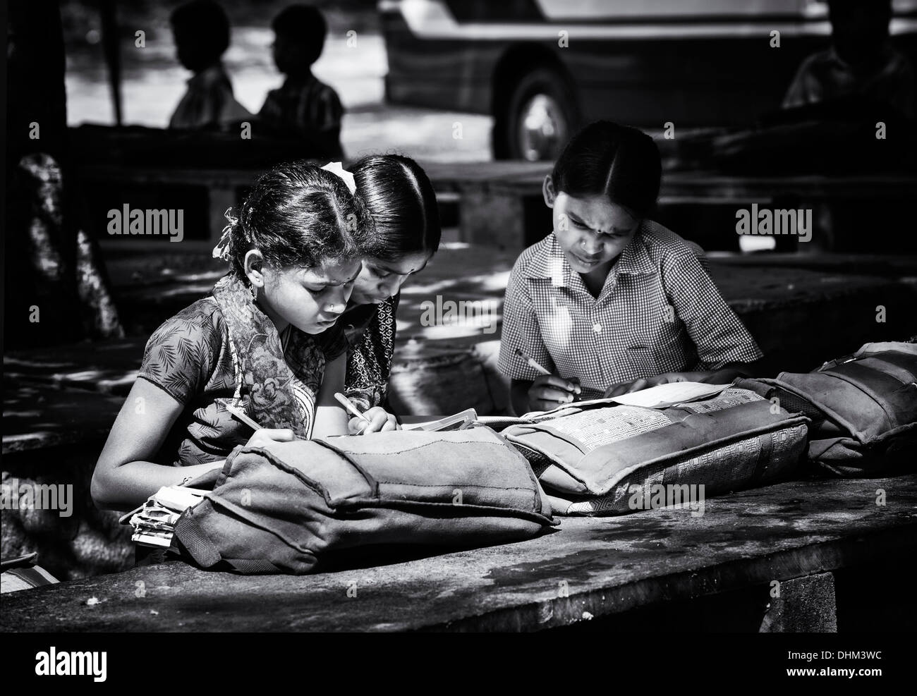 Rural Indian village school girls writing in books in an outside class. Andhra Pradesh, India. Black and white, selective focus. Stock Photo