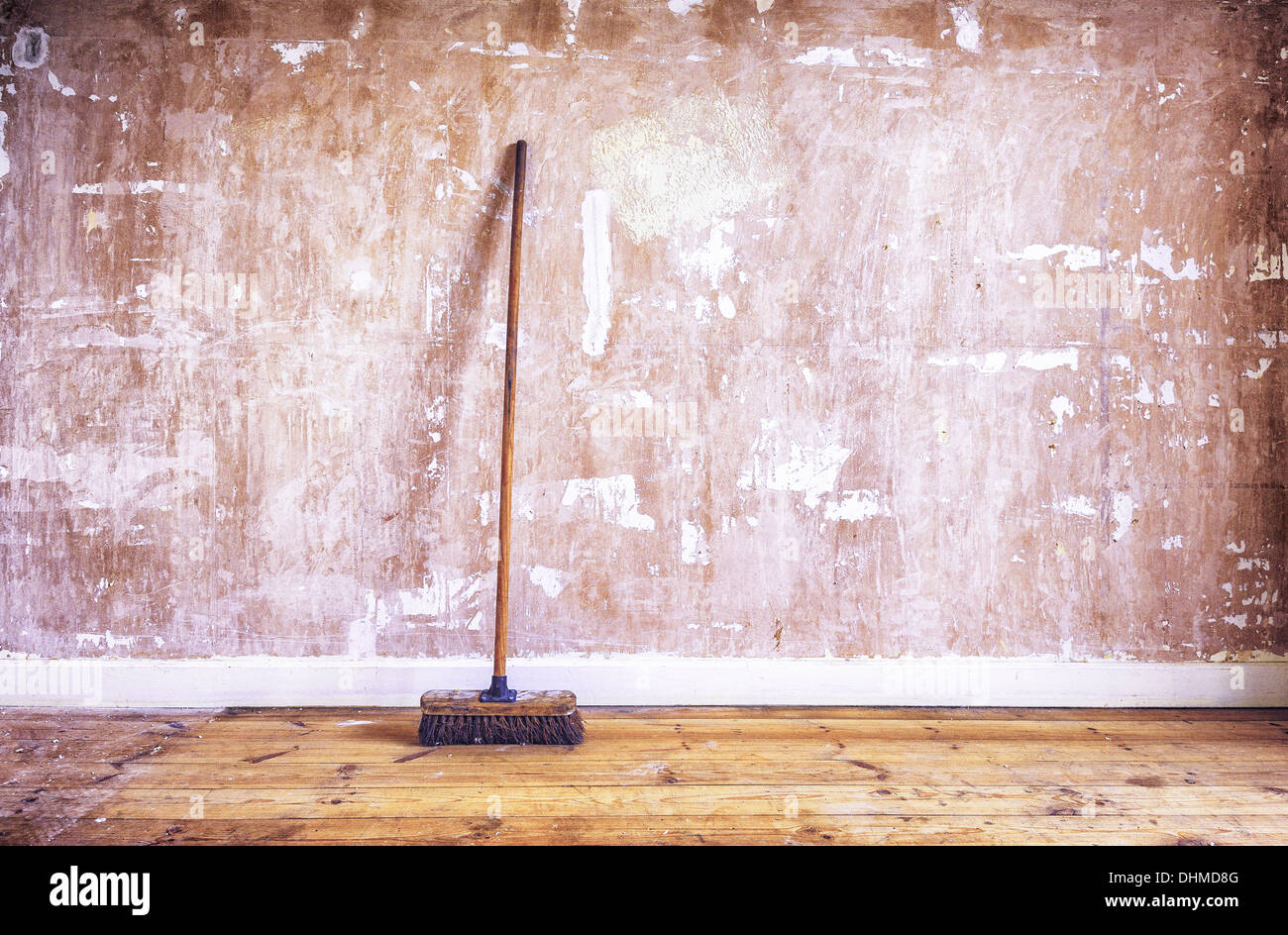 A wooden brush (broom) leaning against a stripped plasterboard wall (drywall) during home decorating improvement renovation Stock Photo