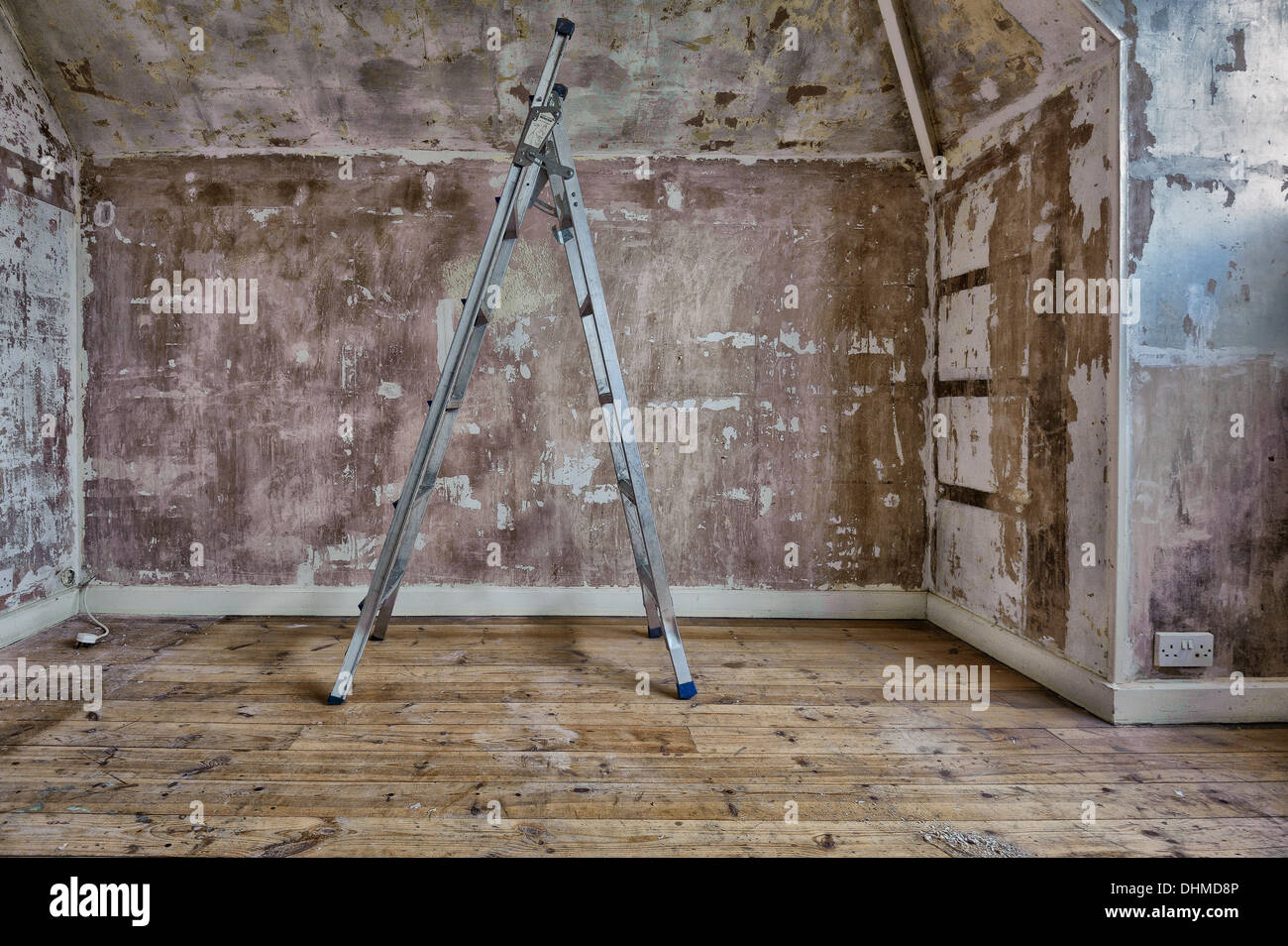 Stepladders on bare wooden floorboards. The room walls are stripped