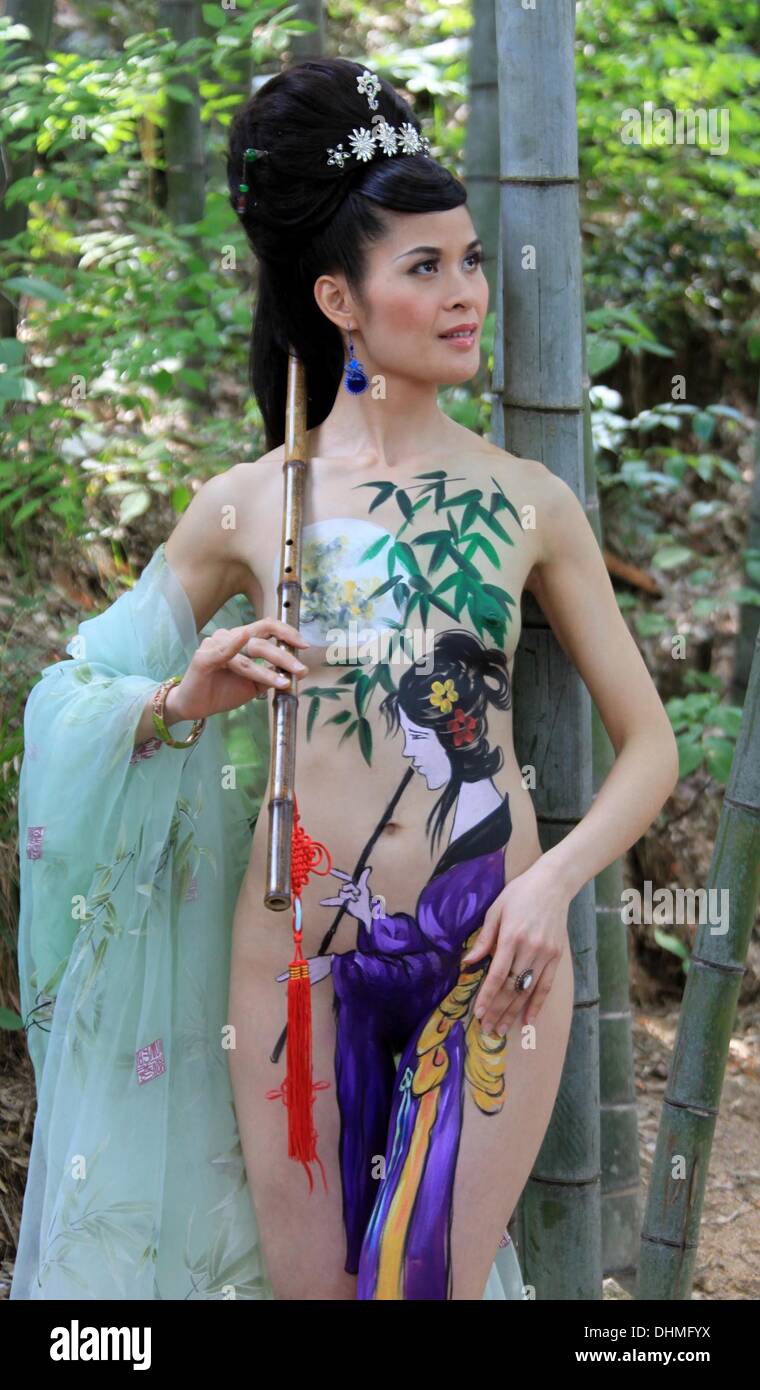 Body Painting  A body art painting model shows off her creativity while playing a bamboo flute in the Huangshan Mountain in China  China - May 2012 Stock Photo