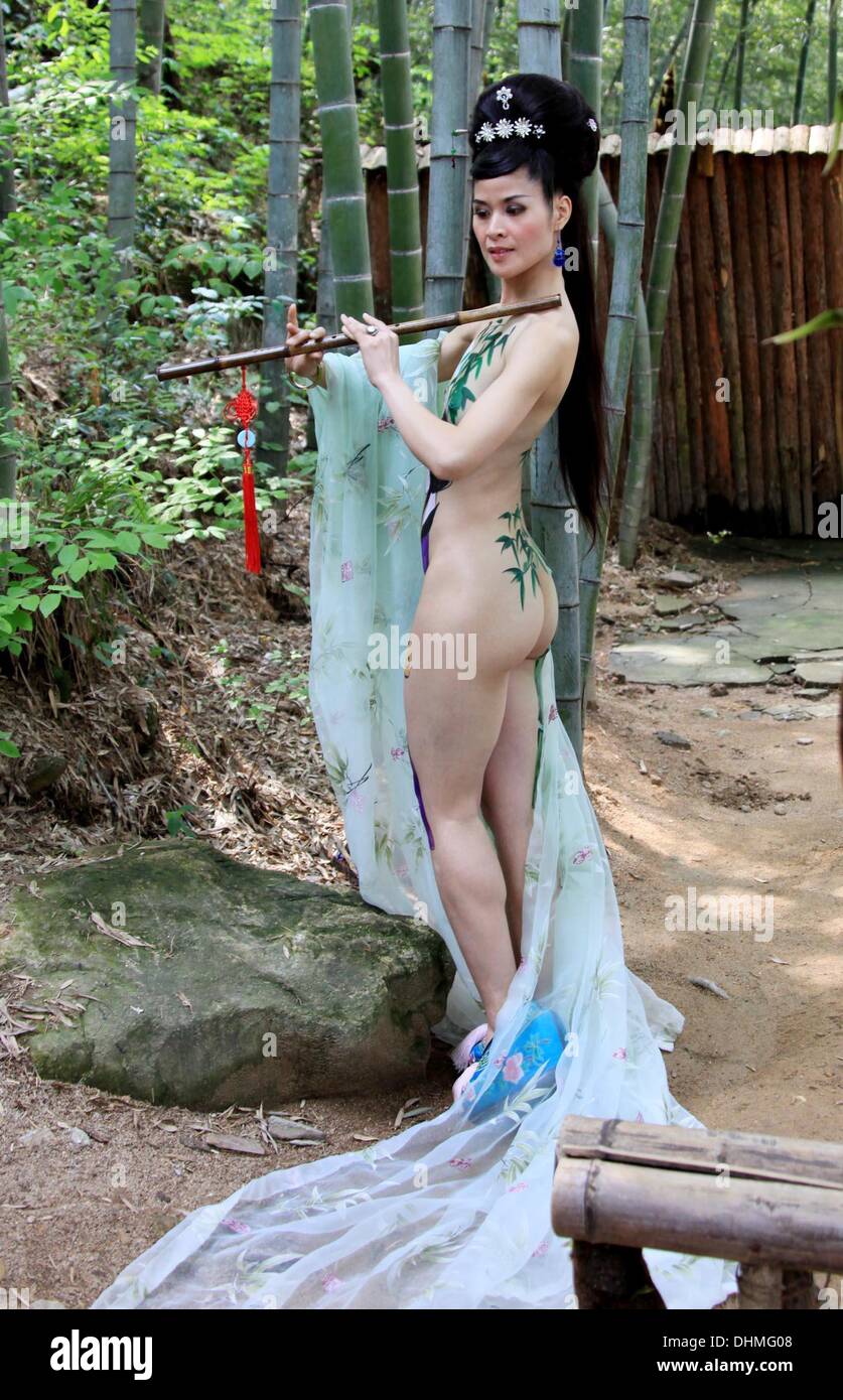 Body Painting  A body art painting model shows off her creativity while playing a bamboo flute in the Huangshan Mountain in China  China - May 2012 Stock Photo