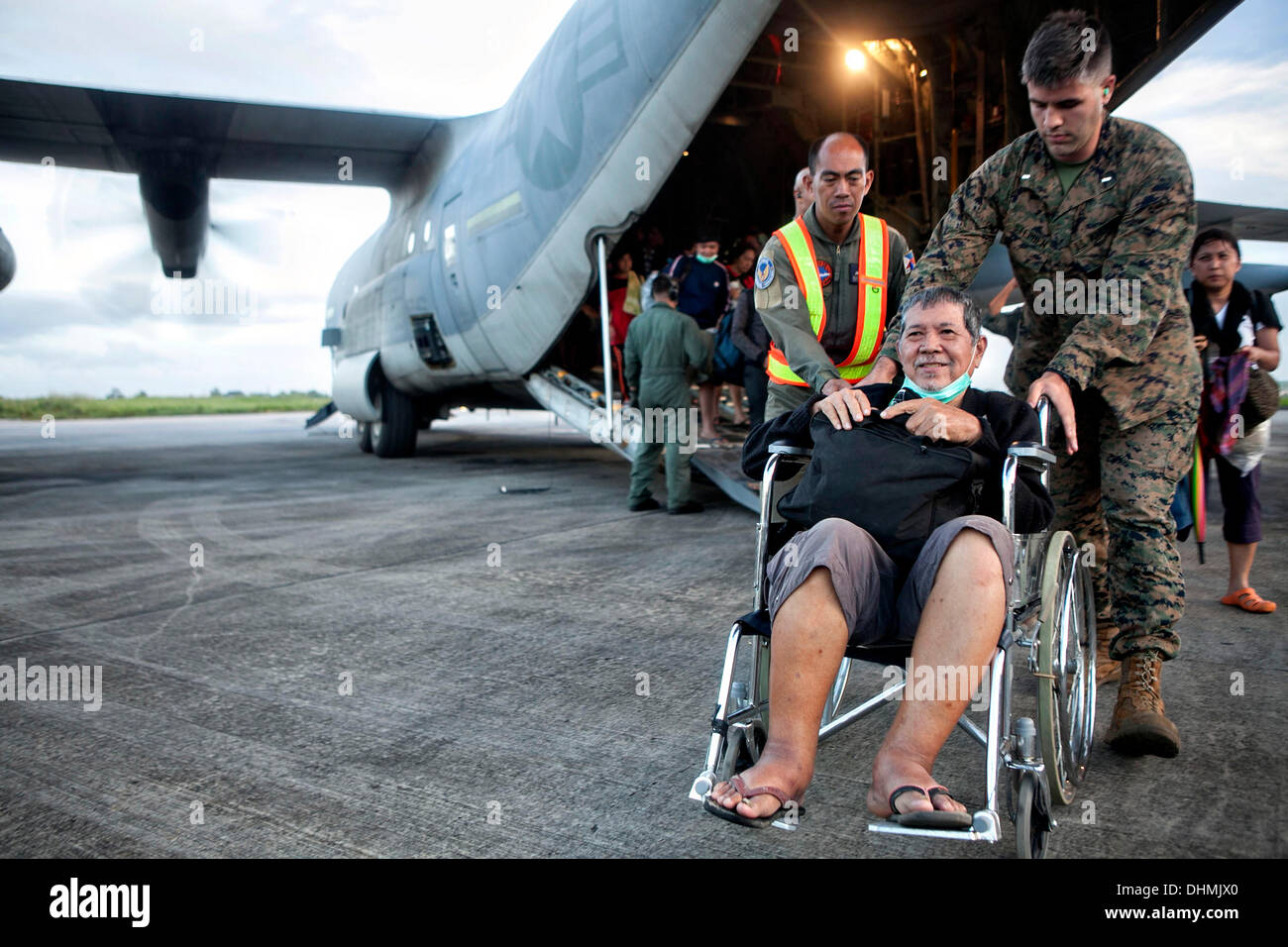 US Marines help offload Filipino civilians out of a U.S. Marine C-130 Hercules aircraft at Villamor Air Base evacuated from Tacloban November 12, 2013 in Manila, Philippines. The super typhoon devastated wide areas of the islands and killed as many as 10,000 people. Stock Photo