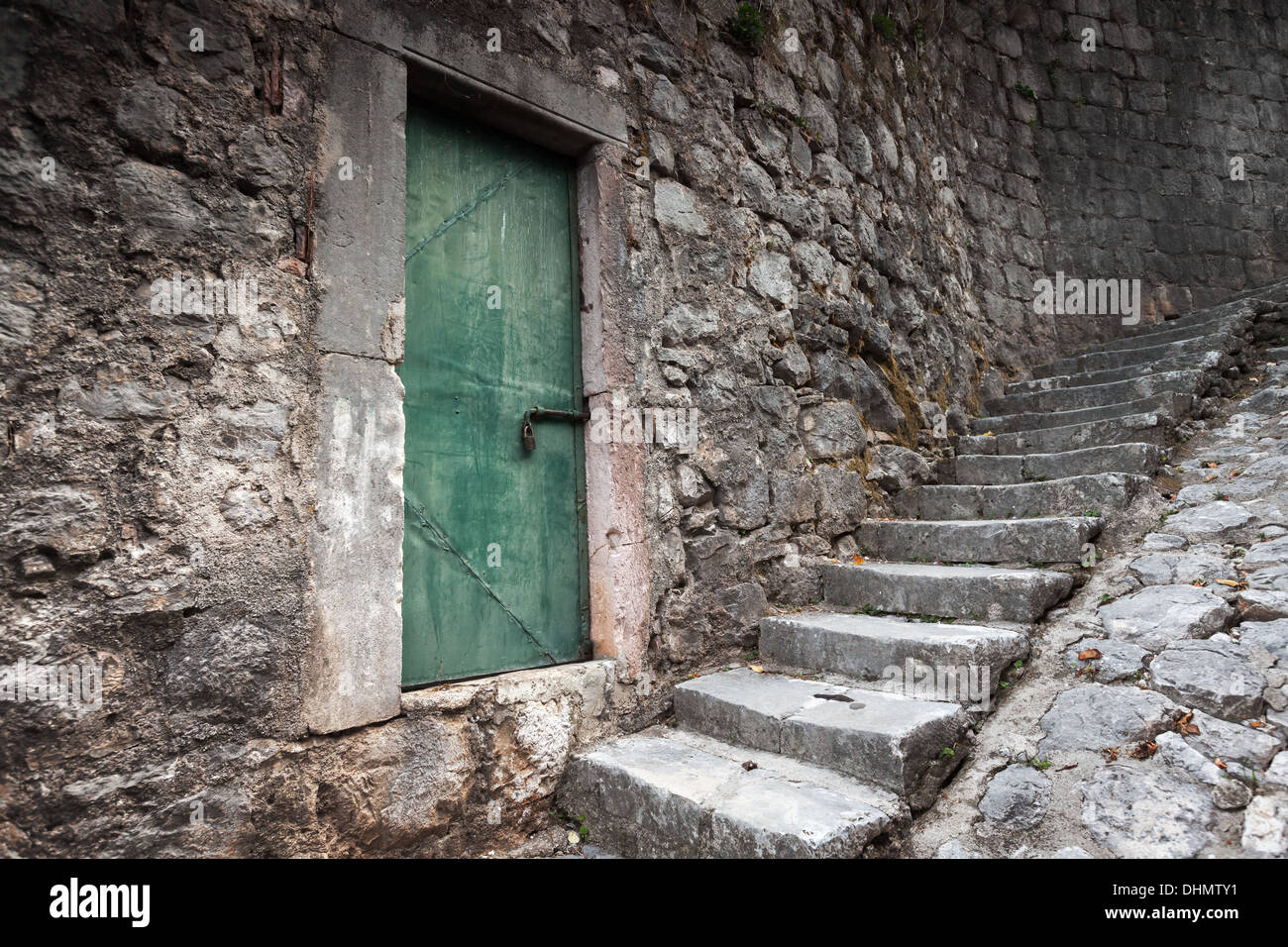 Old locked green door and stone stairway in Perast town, Montenegro Stock Photo