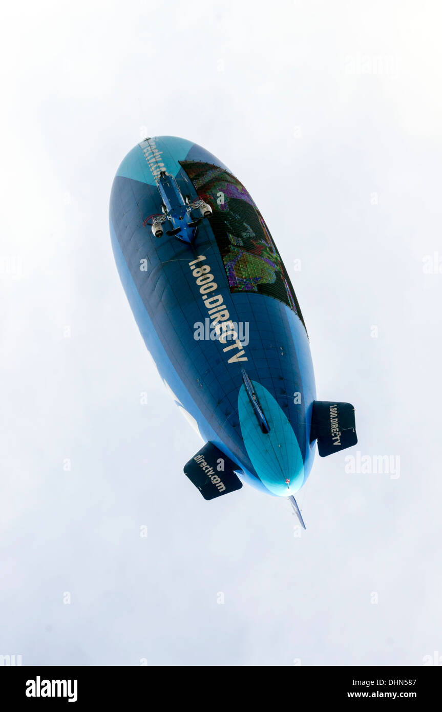 Blue and turquoise hot air blimp navigates above the football stadium advertising DirecTV in Gainesville, Florida, USA. Stock Photo