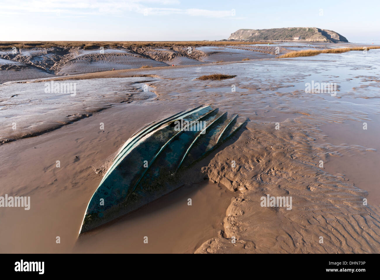 Mud flats at Uphill on the River Axe with a small boat sunk into the dangerous Severn estuary mud, Brean Down in the distance. Stock Photo