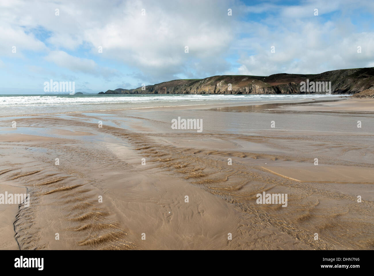 Deserted Newgale Sands Beach with freshwater stream water flowing to the sea and with cliffs and surf in the background. Stock Photo
