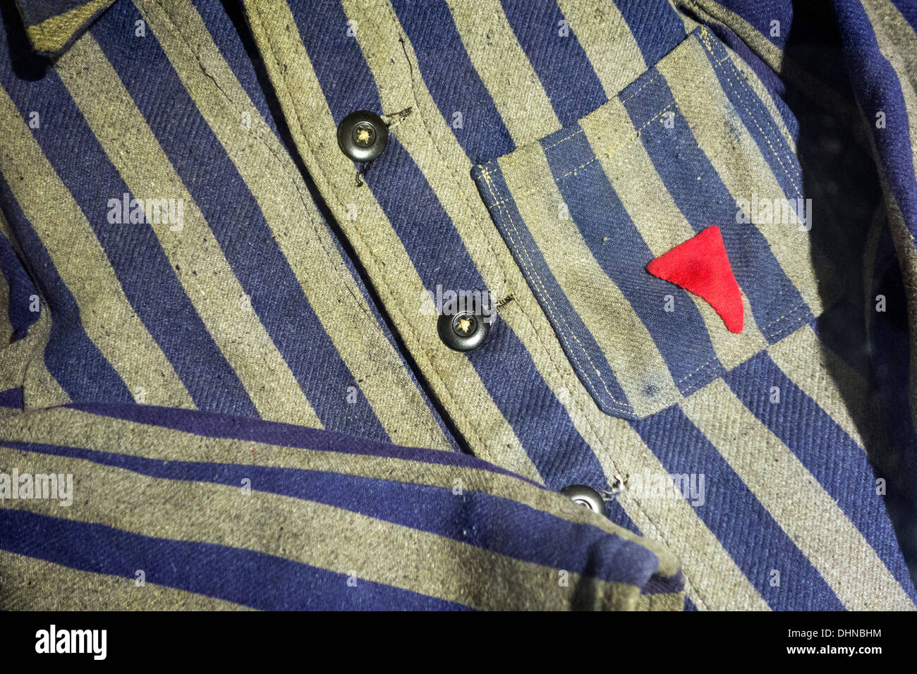 Close up of WW2 Auschwitz prisoner's clothes showing red triangular Nazi concentration camp badge of shame of political detainee Stock Photo