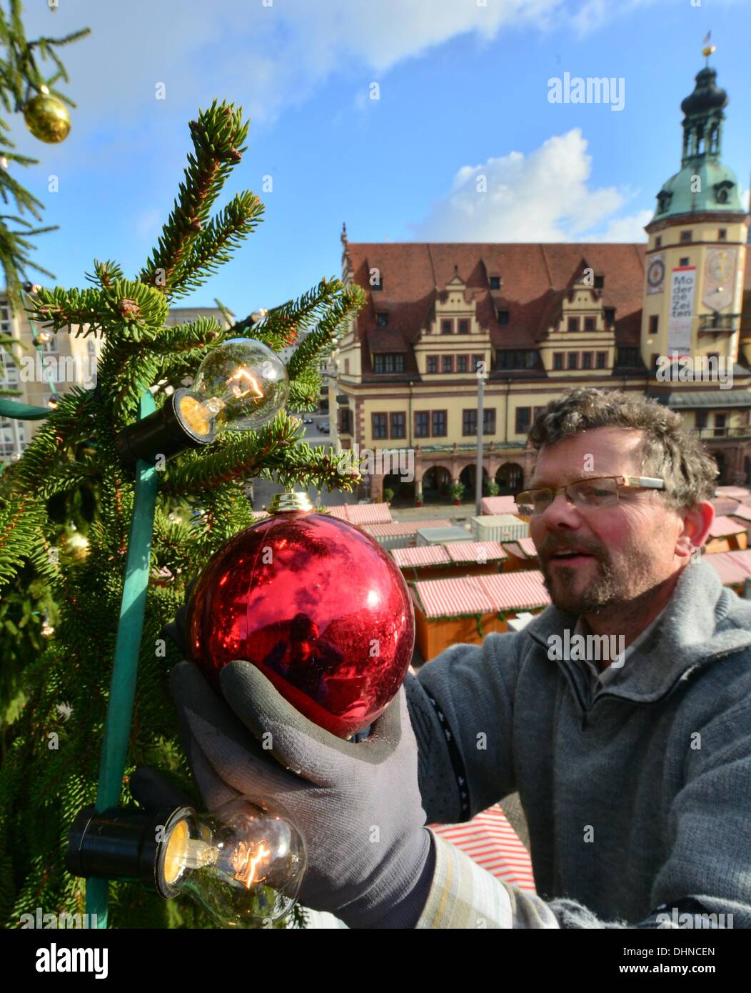 Leipzig, Germany. 13th Nov, 2013. Employee Andreas Gruhne decorates a Christmas tree with 1000 christmas tree baubles and 2000 christmas tree lights on the market square in Leipzig, Germany, 13 November 2013. The 20 metre tall silver spruce was cut from a forest near Markneukirchen in the Vogtland region and is expected to be lit for the kick-off of this years' Christmas market in Leipzig on 26 November 2013. Photo: Hendrik Schmidt/ZB/dpa/Alamy Live News Stock Photo