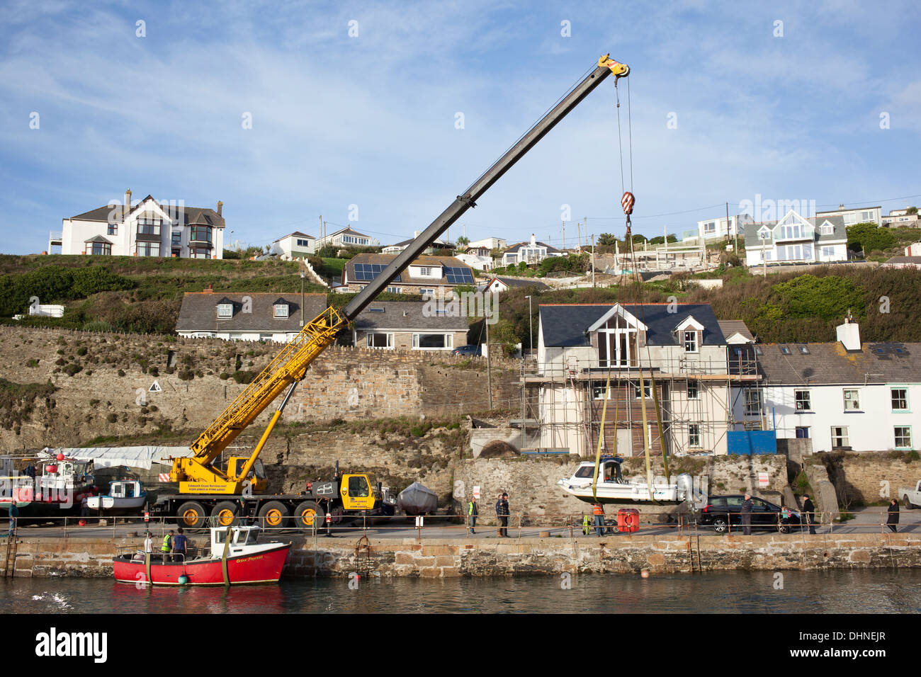 A large yellow crane raising boats out of Portreath harbour as the winter approaches, Cornwall England. Stock Photo