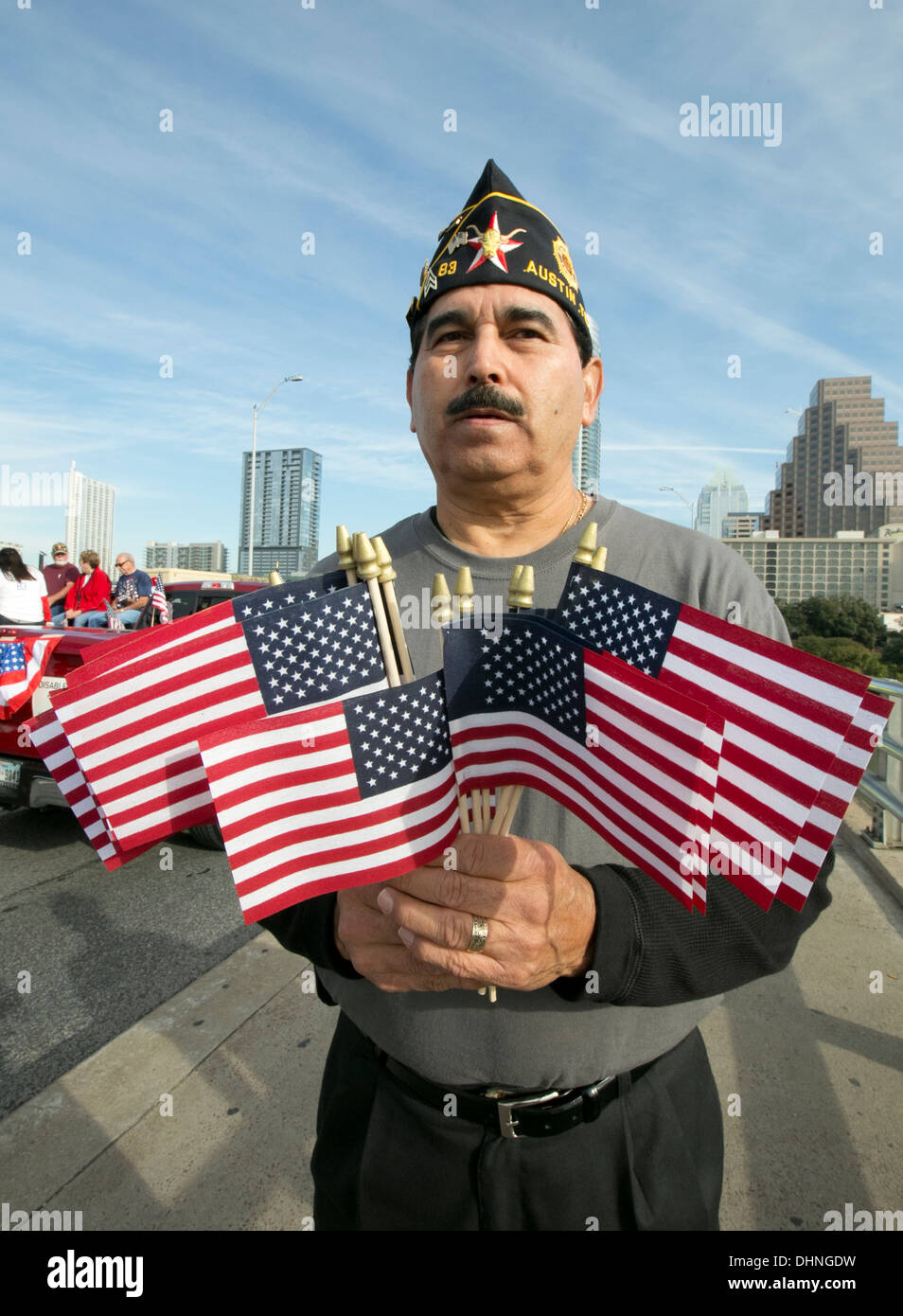 Male Hispanic military veteran holds several small American flags during a Veteran's Day parade in Austin, Texas Stock Photo