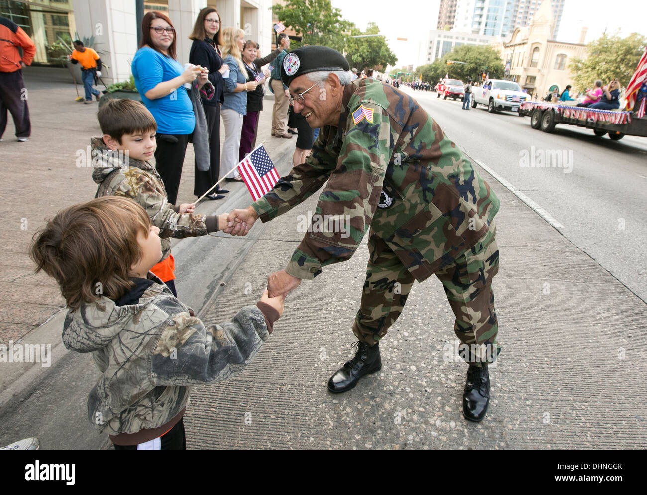 Vietnam war male Hispanic veteran, greets, shakes hands with crowd, children during a Veteran's Day parade Stock Photo