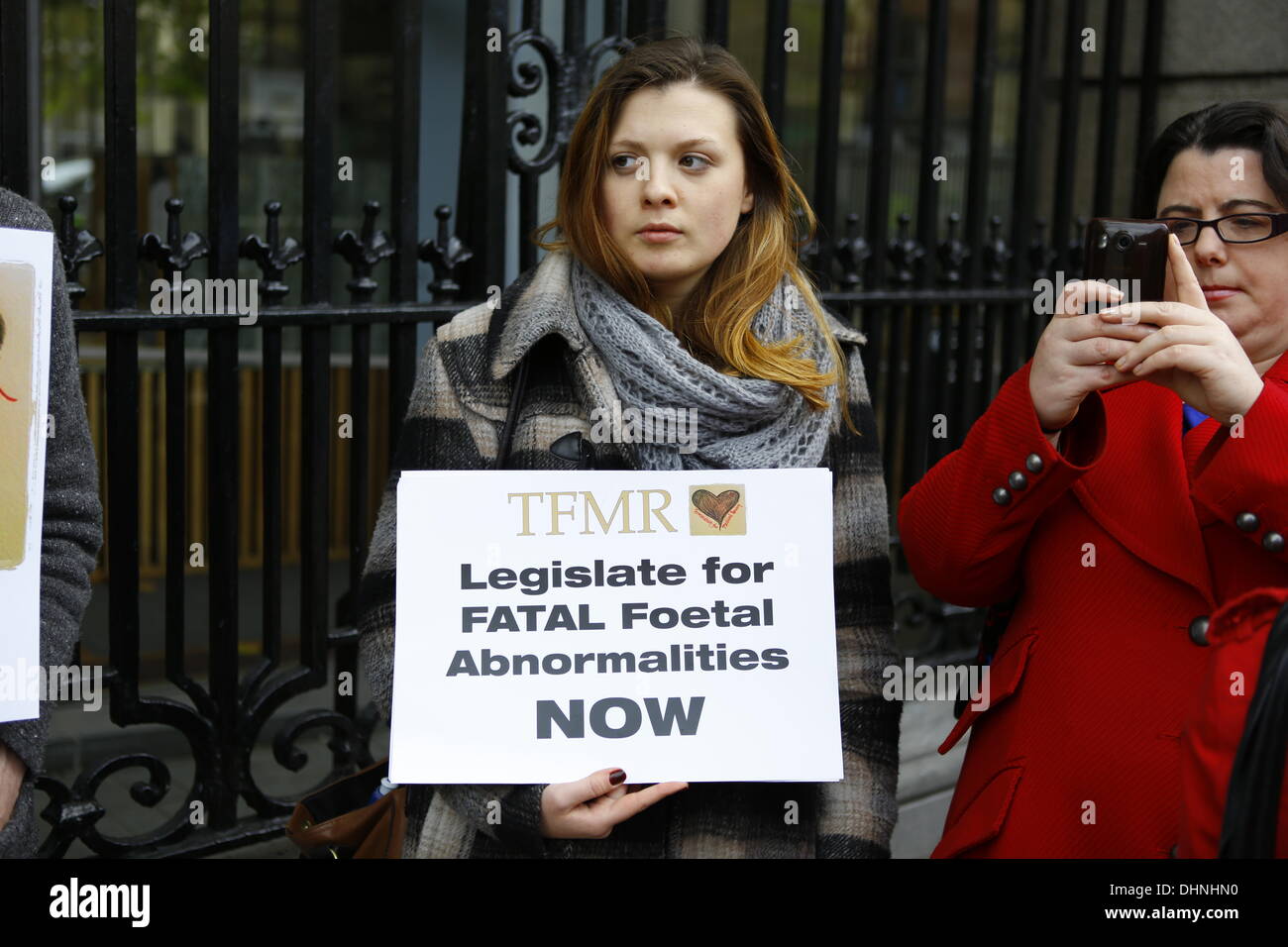 Dublin, Ireland. 13th November 2013. A protester stands outside the Dail (Irish parliament) holding a sign that reads 'TFMR Legislate for FATAL Foetal Abnormalities NOW'. The Center of Reproductive Rights brought a case against Ireland to the UN Human Rights Committee on behalf of Amanda Mellet. She had to travel to the UK for an abortion after she had been diagnosed with fatal fetal abnormality during her pregnancy. Abortions for fatal fetal abnormalities are illegal in Ireland. Credit:  Michael Debets/Alamy Live News Stock Photo