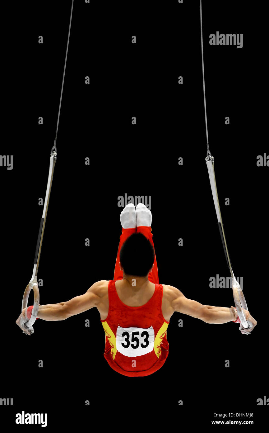 Back view with a gymnast performing on the rings apparatus Stock Photo