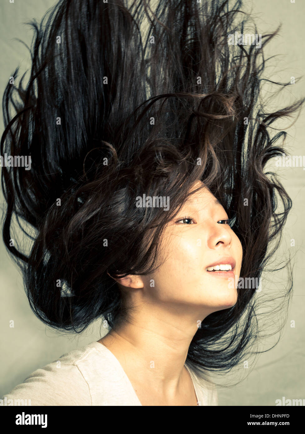 Young woman flicking her hair and posing, with fashion tone and background Stock Photo