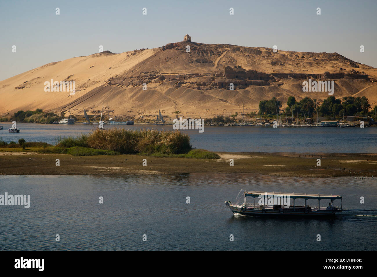 View across the Nile at Aswan to Qubbet al Hawa atop the far slope. Stock Photo