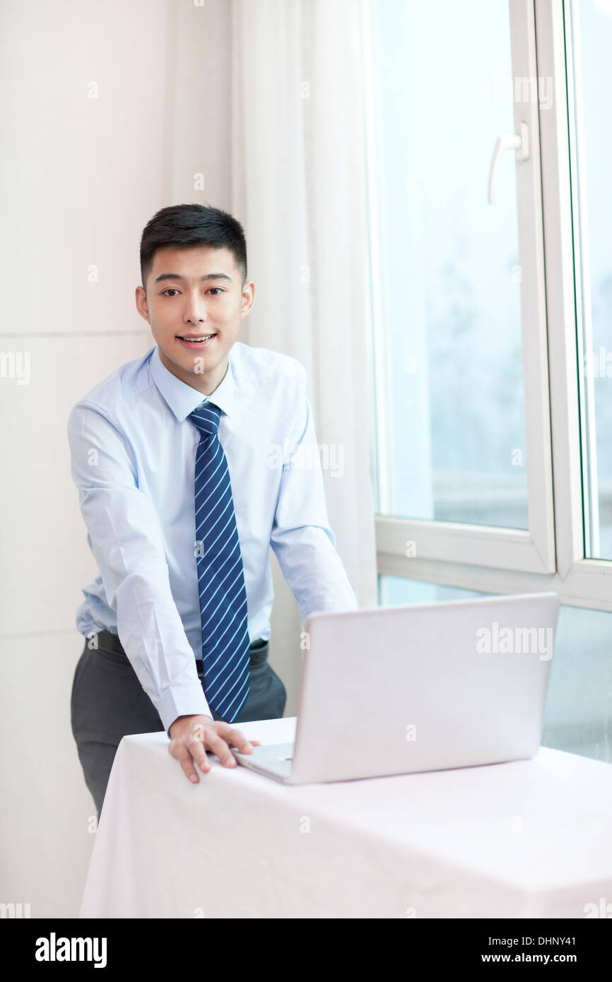 Businessman standing, holding a laptop, smiling Stock Photo