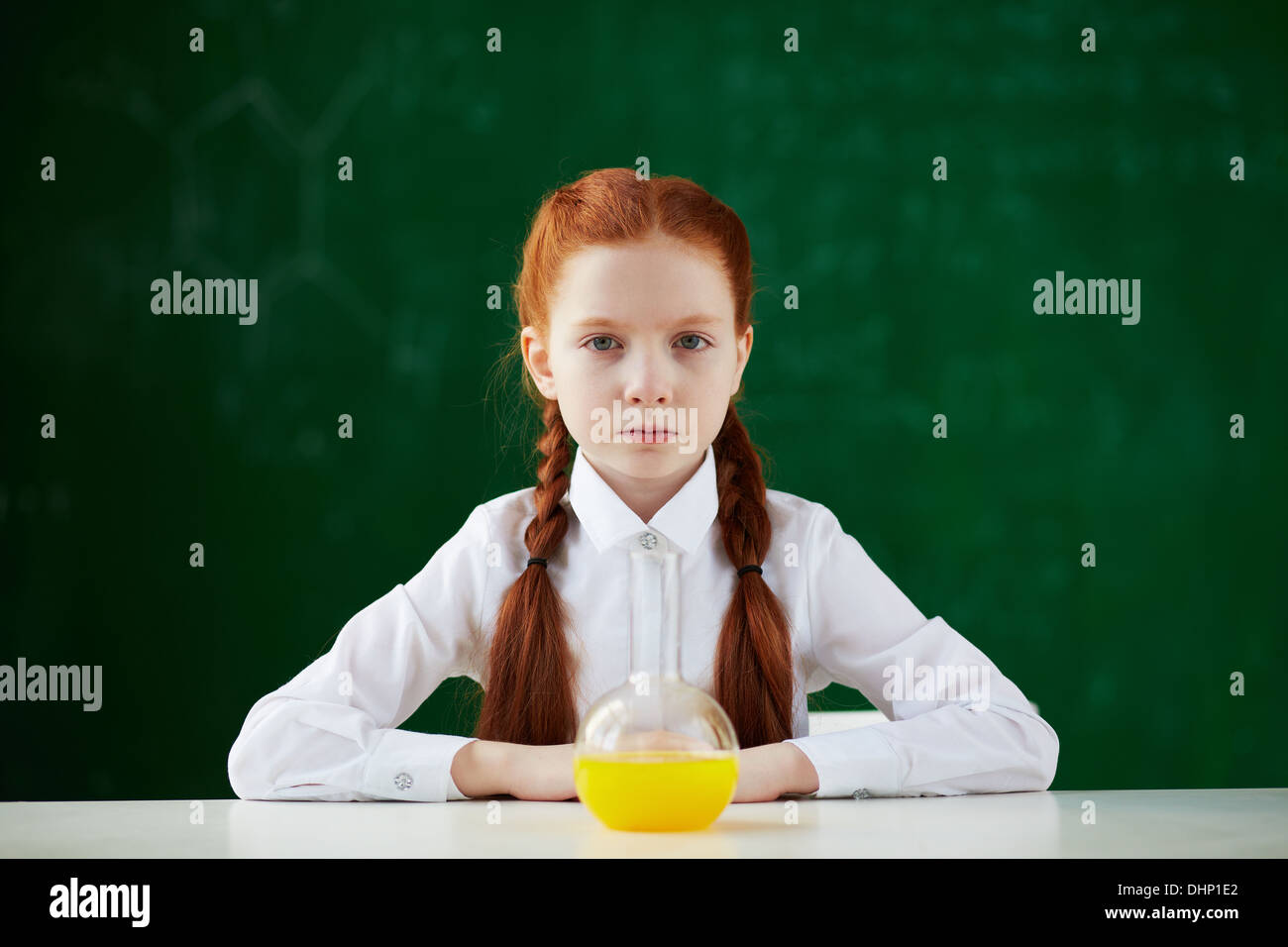 Portrait of schoolgirl sitting at workplace with chemical liquid in front Stock Photo
