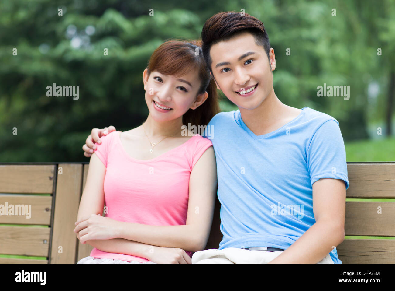 Happy young couple sitting on park bench Stock Photo - Alamy