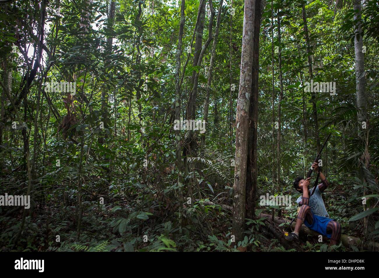 April 27, 2013 - Poti-Kro, Para, Brazil - A young man sights down the barrel of his shotgun while hunting in the jungle. Hunting trips are quiet affairs with many stops to listen for game. Experienced hunters can recognize and mimic many animal sounds. The indigenous Xikrin people live on the Bacaja, a tributary of the Xingu River, where construction of the Belo Monte Dam is reaching peak construction. Some scientists warn that the water level of the Bacaja will decrease precipitously due to the dam. (Credit Image: © Taylor Weidman/ZUMA Wire/ZUMAPRESS.com) Stock Photo