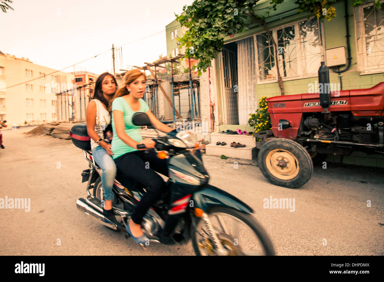 Two girls riding a scooter in Soma, Turkey 2013 Stock Photo