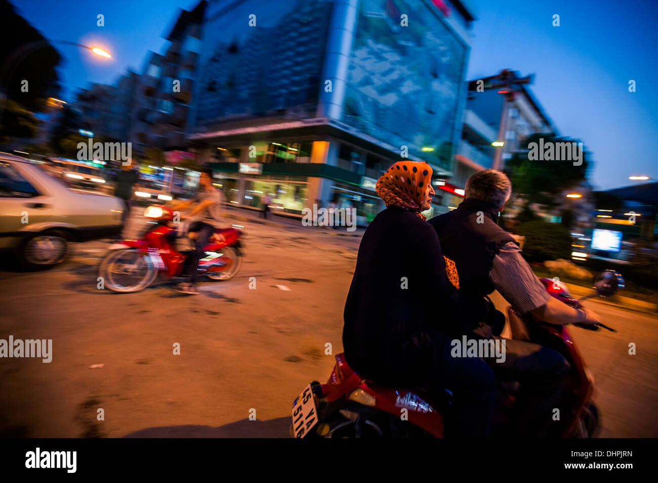 People riding their scooters at night.  Intersection of Soma, Turkey 2013 Stock Photo