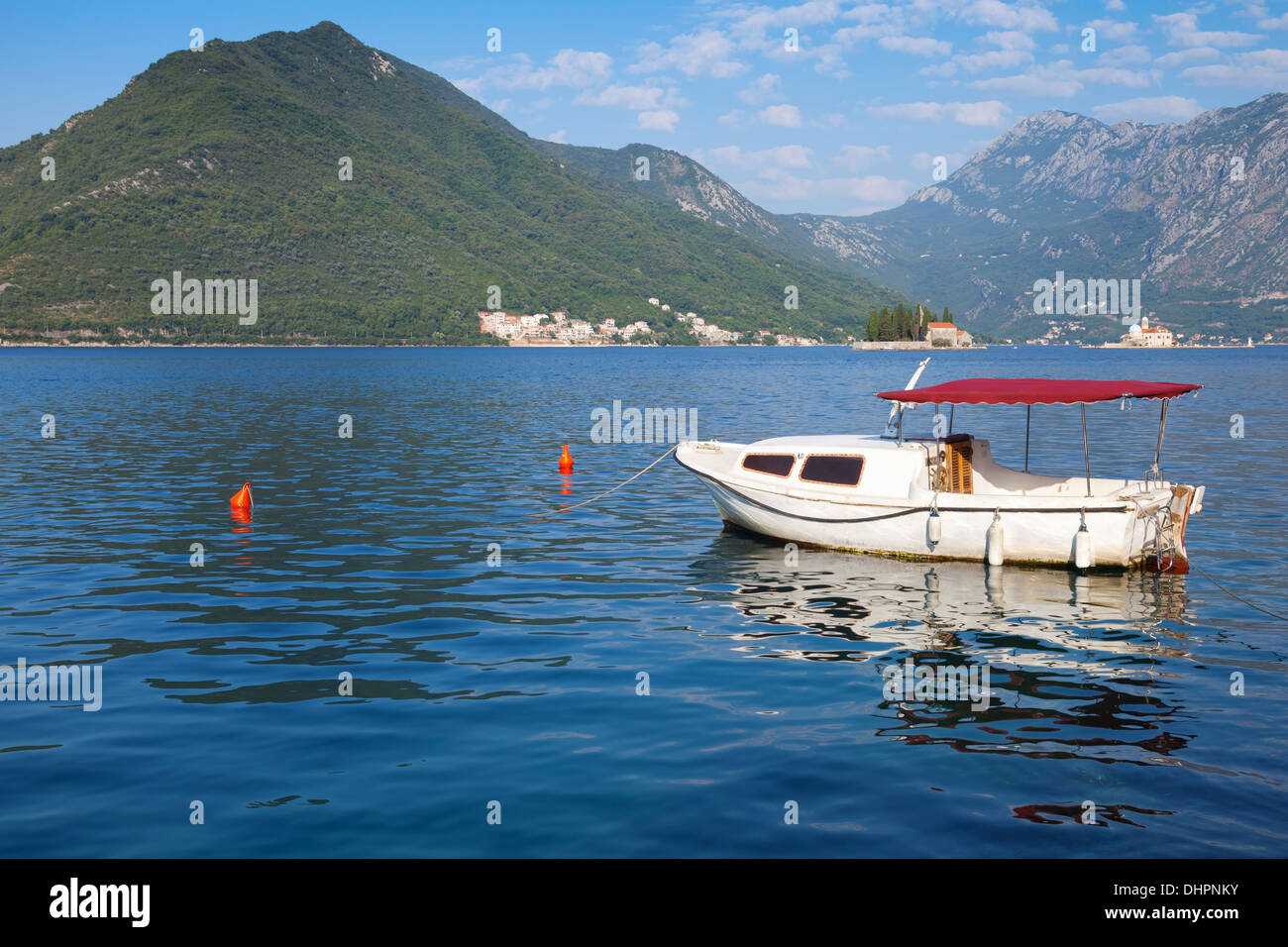 Small white pleasure boat floats moored in Perast town, Kotor Bay, Montenegro Stock Photo