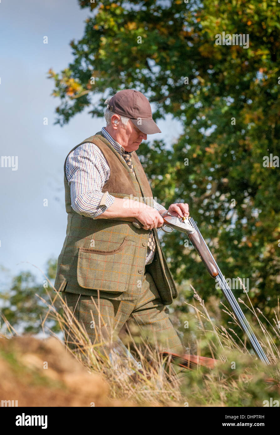 A man loading a shotgun stood  waiting for the start of a pheasant shoot in England Stock Photo