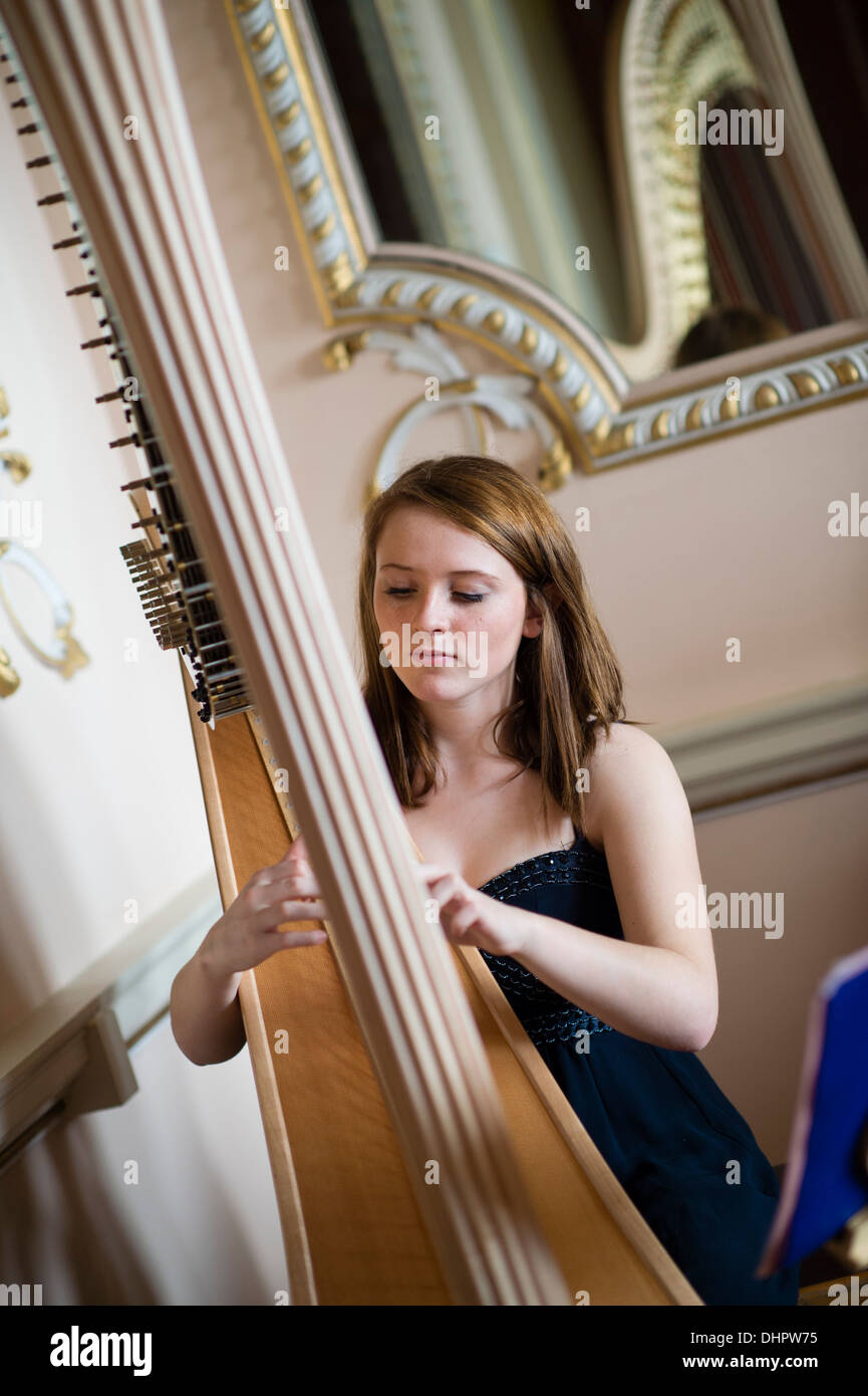 A young woman playing traditional harp music at a Wedding Fayre Fair at Nanteos Mansion,, Aberystwyth Wales UK Stock Photo