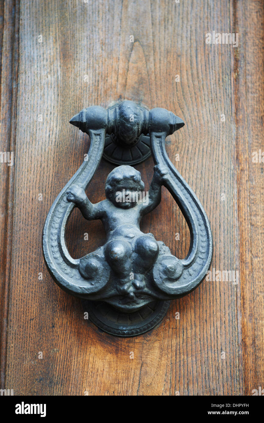 Door Knocker in cast iron on wooden door with a baby or Cherub as the main design Stock Photo