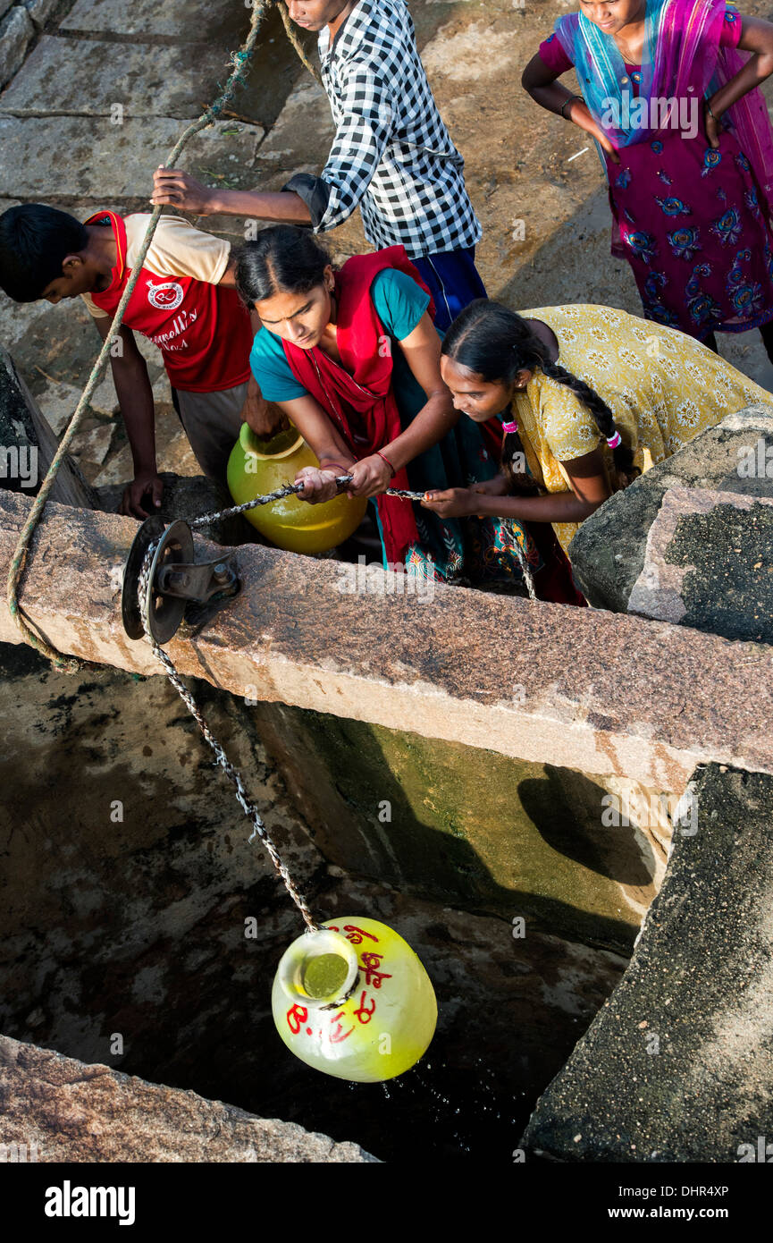 Indian teenage girls and boys drawing water from a well in a rural Indian village street. Andhra Pradesh, India Stock Photo