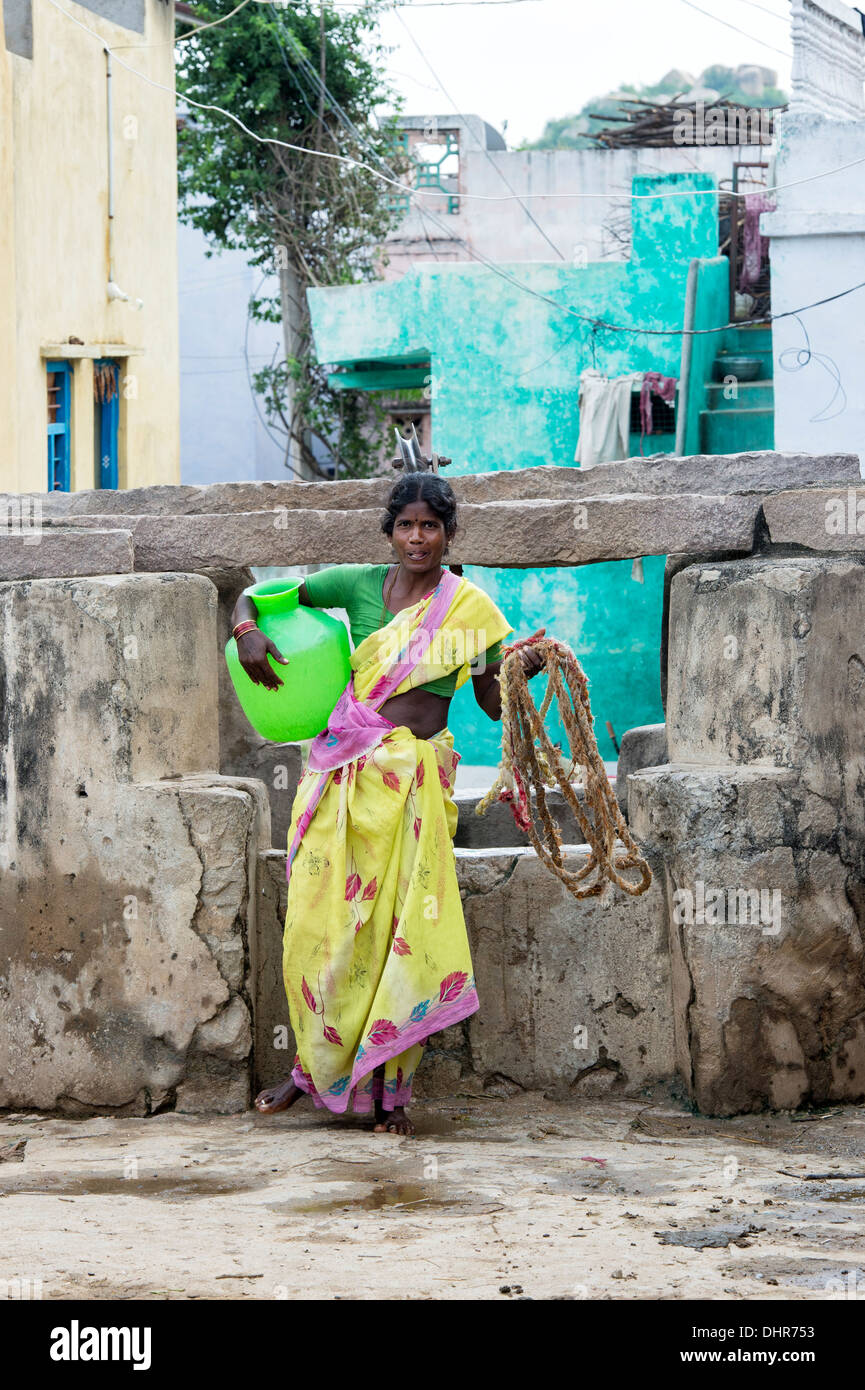 Indian woman holding a plastic pot of water drawn from a well in a rural Indian village street. Andhra Pradesh, India Stock Photo