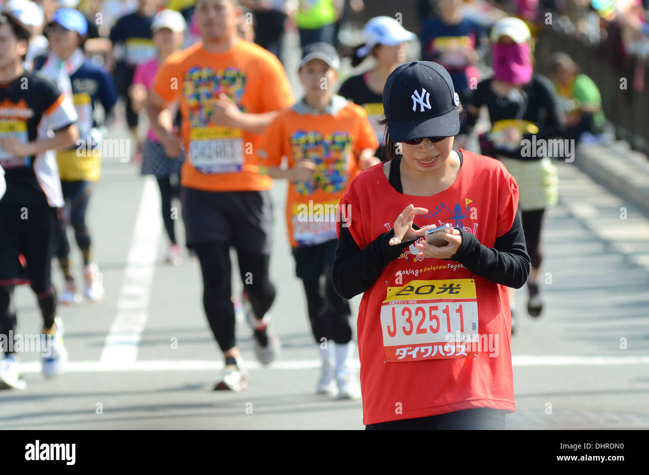 A runner using her smartphone during a marathon in Osaka, Japan. Stock Photo