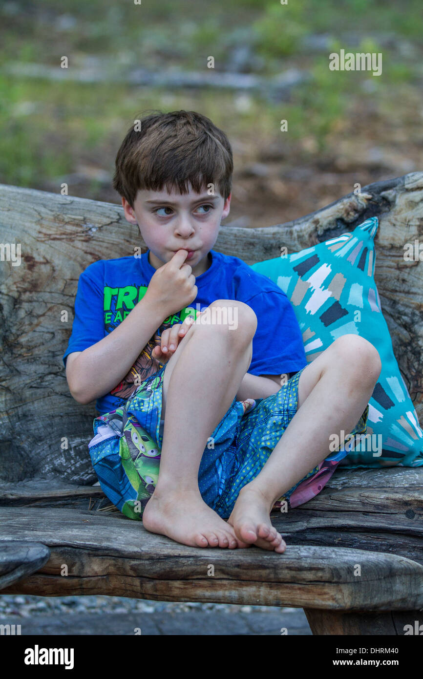 A cute, model released young boy, sitting outside, having a thoughtful moment. Stock Photo